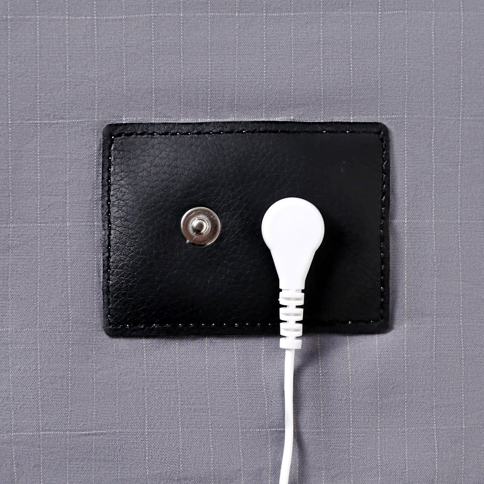 Close-up of the snap connection area on a gray Aisiting grounding fitted sheet